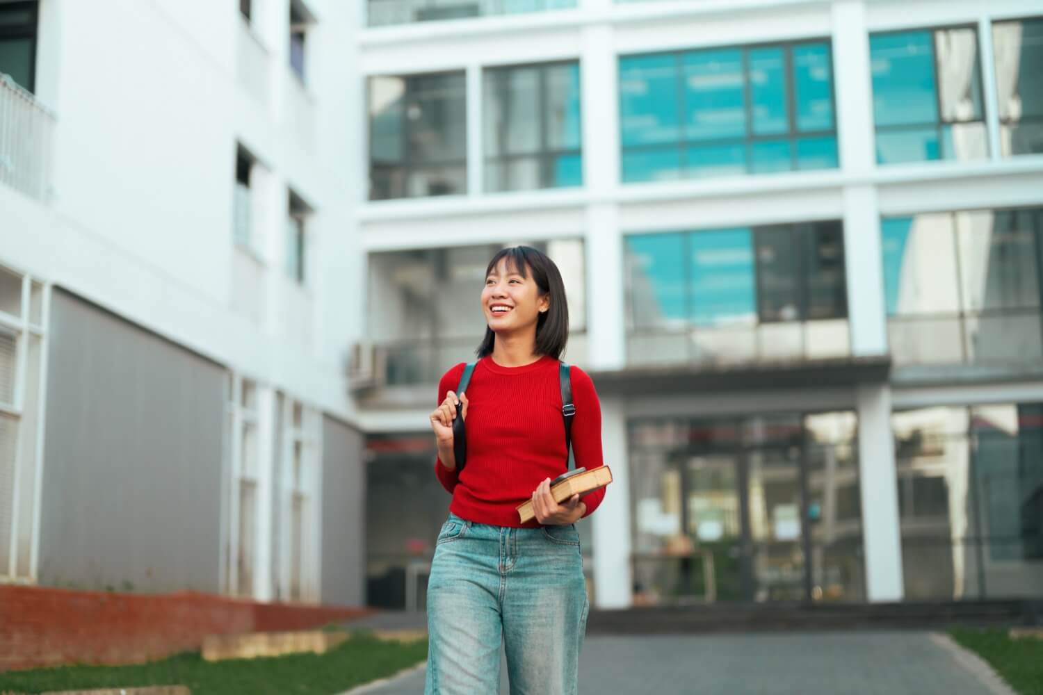 Happy female student walking outdoors on university